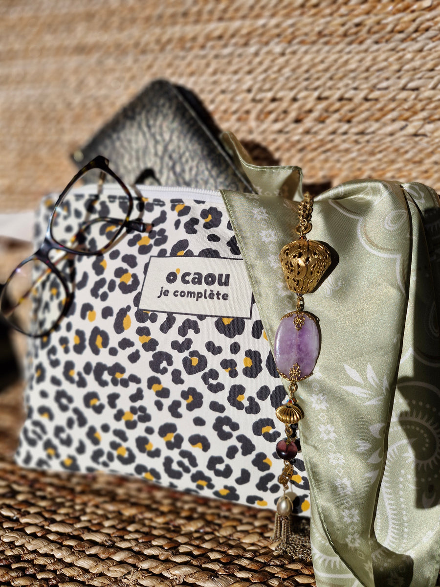 Pochette léopard avec lunettes et bijoux posés dessus