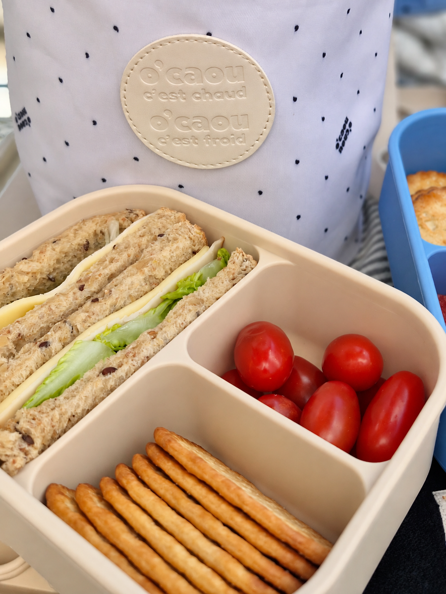 Lunch box ouverte avec son séparateur : fraises et amandes de chaque côté, couvercle posé à côté