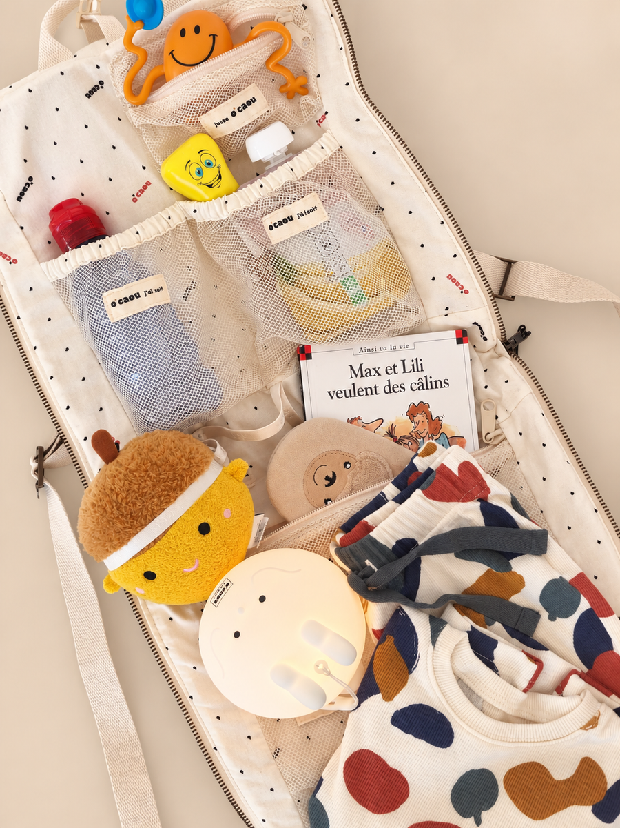 Sac ouvert : peluches, livre d'histoire, gourde et vêtements