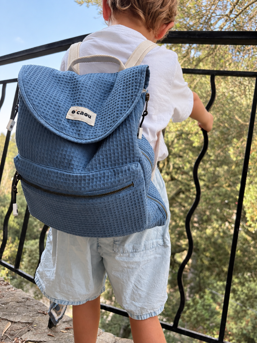 Enfant vu de dos avec le sac bleu