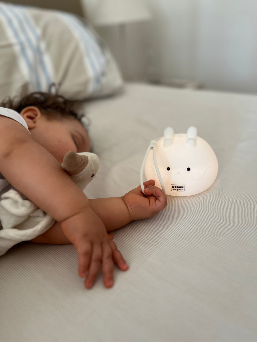 Bébé endormi qui garde la main sur sa veilleuse allumée