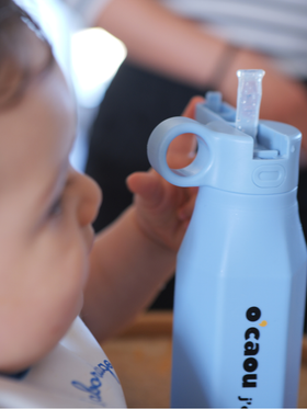 Enfant qui boit à sa gourde beige
