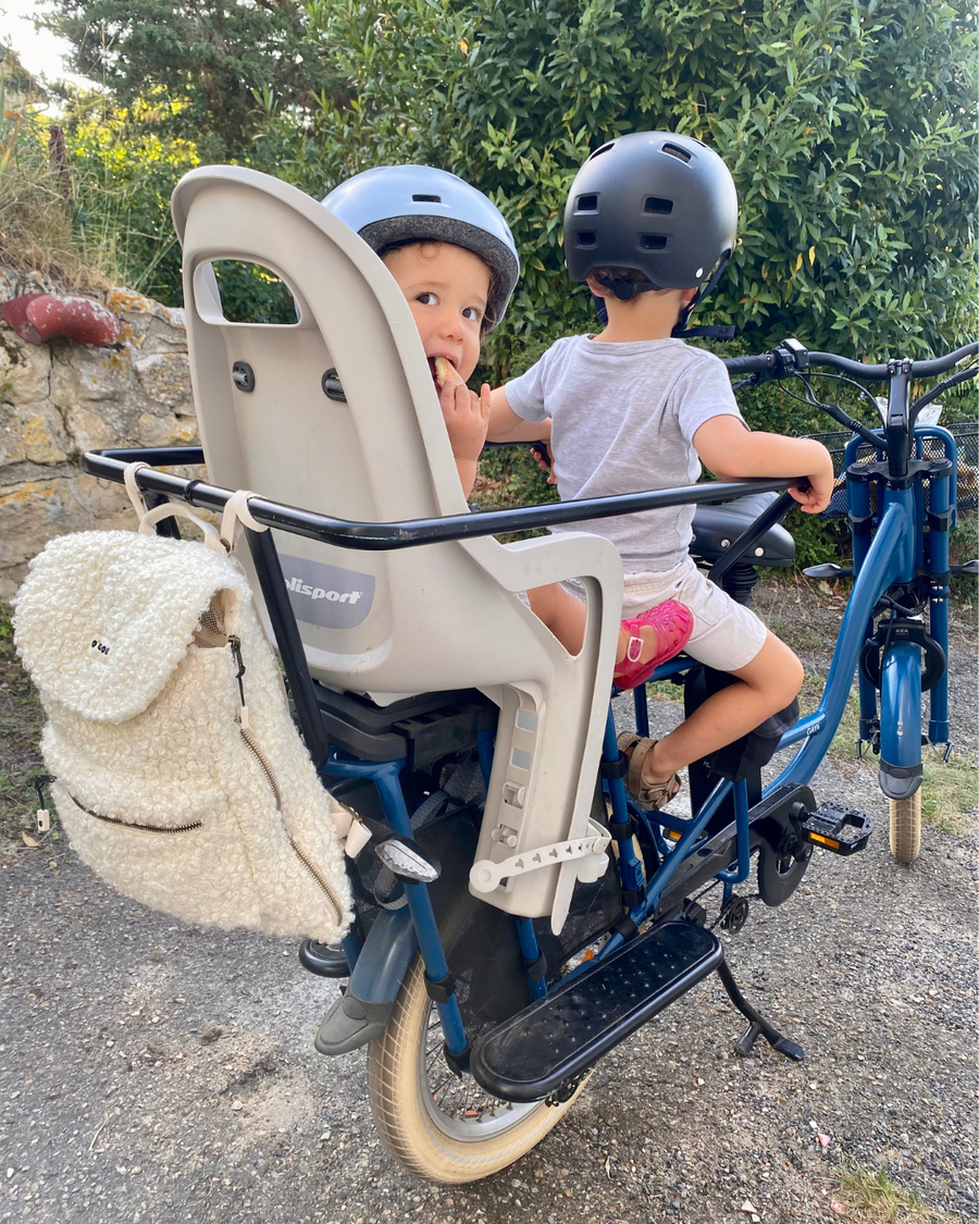 Sac O'CAOU accroché à la barre avant d'un vélo, deux enfants casqués installés derrière