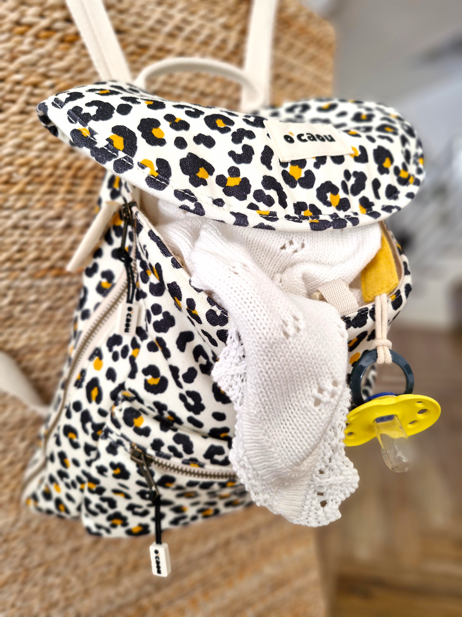 Sac léopard ouvert, couverture blanche et tétine rangées dedans