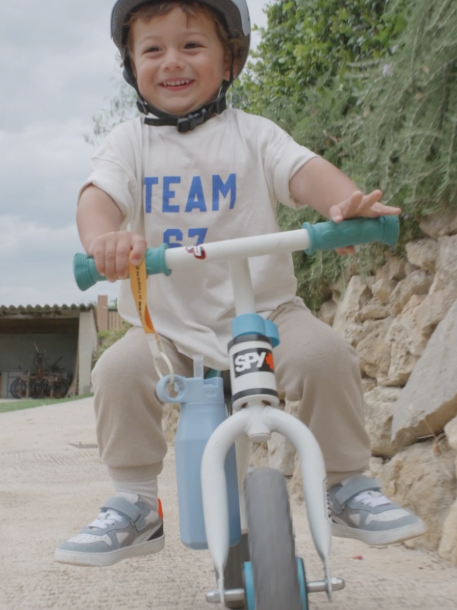 Enfant à vélo, doudou accroché au guidon par sa poignée