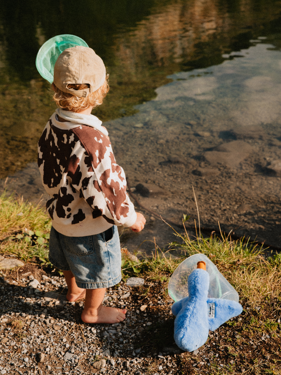 Enfant au bord de l'eau, doudou bleu dans son filet