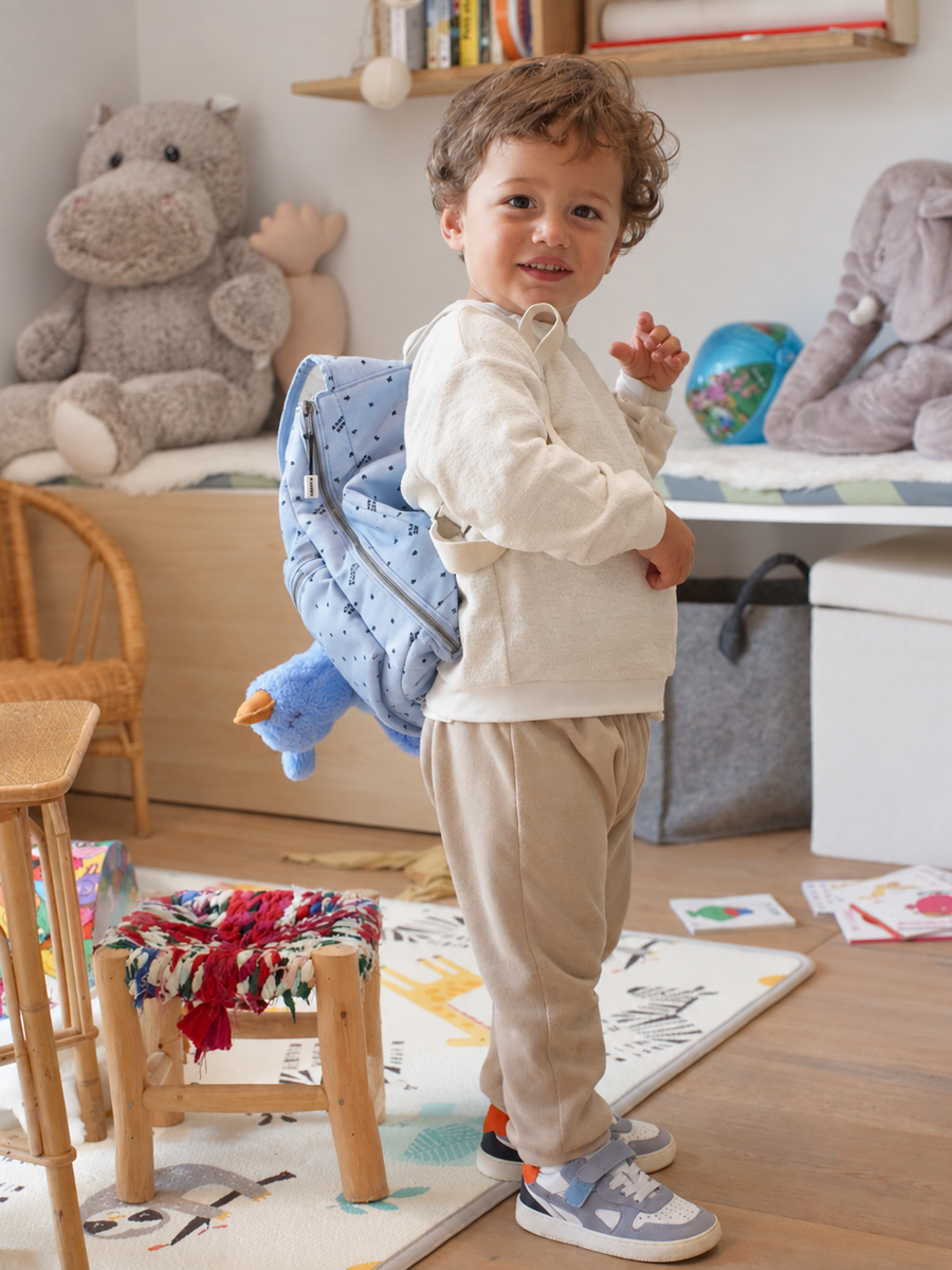 Enfant qui marche dans la rue avec son sac à dos bleu